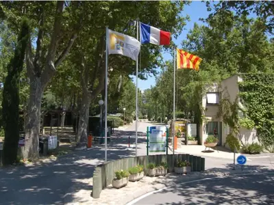 three flags on poles in a street with trees at Mobil-home 32m² avec terrasse, 3 chambres à Cavaillon, 8 pers. - API-1-52-1384 in Cavaillon