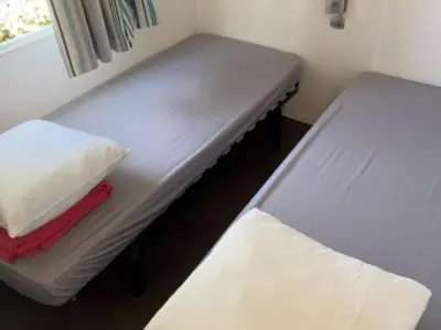 a small room with two beds and a window at Mobil-home confortable, 2 chambres, 4 personnes - API-1-52-1390 in Cavaillon