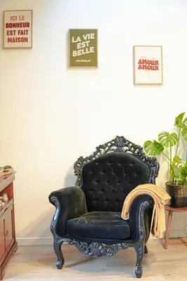 a black chair in a living room with a sign at Maison bord de rivière - Le Thor in Le Thor