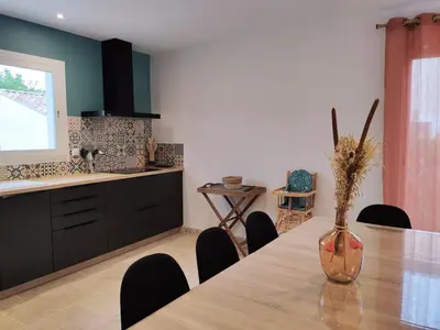a kitchen with a table with chairs and a vase with flowers at New Villa in Provence La Modèna in Modène