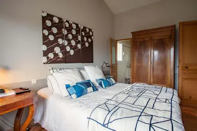 a bedroom with a large white bed with blue pillows at La Maison des Restanques in Cabrières-dʼAvignon