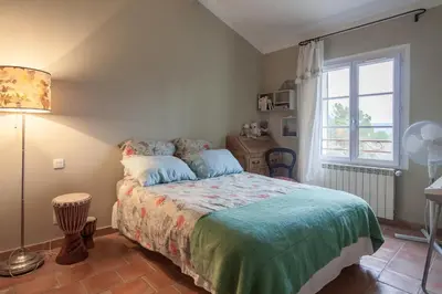 a bedroom with a bed and a window at La Maison des Restanques in Cabrières-dʼAvignon