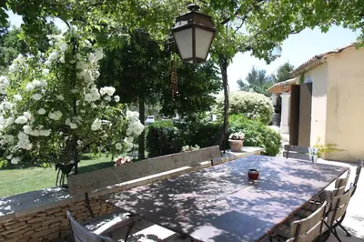 a table with chairs and a lamp in a yard at La Maison des Restanques in Cabrières-dʼAvignon
