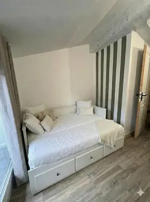 a bed with white sheets and pillows in a room at Maison de ville climatisée avec toit-terrasse privatif in Monteux