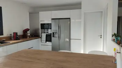 a kitchen with white cabinets and a stainless steel refrigerator at Villa la grande Bastide in Oppède