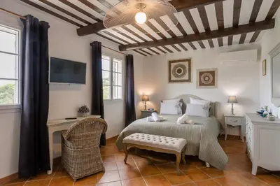 a bedroom with a bed and a table and a tv at Bastide Vallonia Luxury & Serenity in the Heart of the Luberon in Murs