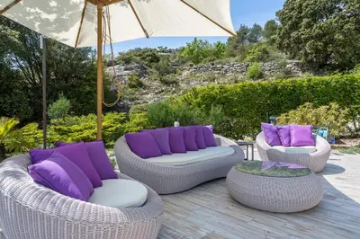 three wicker chairs with purple pillows and an umbrella at Bastide Vallonia Luxury & Serenity in the Heart of the Luberon in Murs