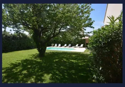 a pool with chairs and a tree in a yard at Les Abricotiers in Caromb
