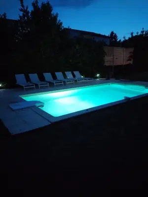 a swimming pool at night with chairs and lights at Les Abricotiers in Caromb