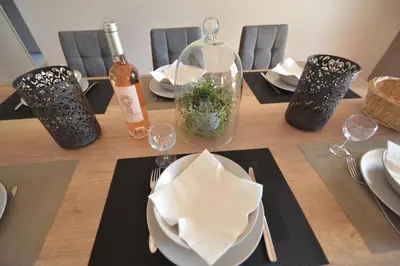a table with plates and glasses and a bottle of wine at Les Abricotiers in Caromb