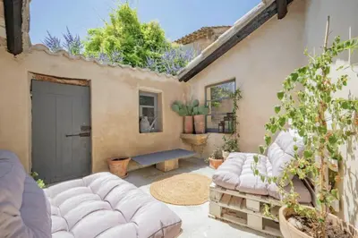 a patio with a white couch and a bench at Artist's House In The Heart Of Lourmarin in Lourmarin