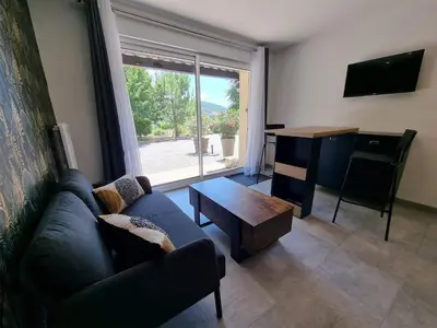 a living room with a couch and a table and a desk at Gîtes de la Coupière Le Mûrier in Aubenas-les-Alpes
