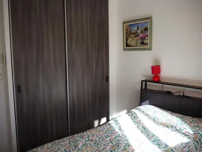 a bedroom with a bed and a wooden closet at Holiday Home by Interhome in Vernègues