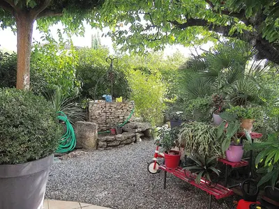 a garden with potted plants and a red wagon at Holiday Home by Interhome in Vernègues
