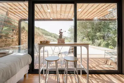a room with a table and two stools in front of a window at Sous les étoiles du Luberon, Tiny House, Ménerbes in Ménerbes