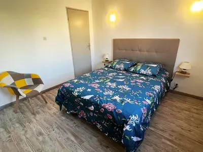 a bedroom with a bed with a blue comforter and a chair at Appartement Spacieux avec Balcon in Carpentras