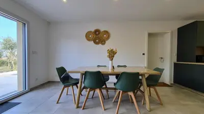 a dining room with a wooden table and green chairs at Villa Quercus Design Piscine et Loisirs in Ménerbes