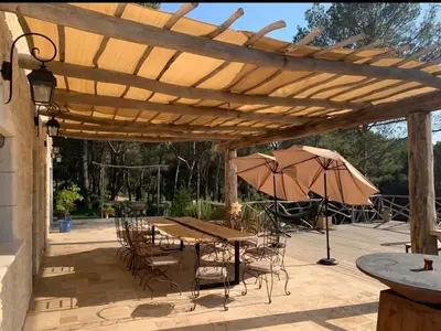 a wooden pergola with a table and chairs and an umbrella at Villa Luxury Lagoon - Aix en Provence in Ventabren