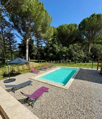 a swimming pool with purple chairs and an umbrella at 4-bedroom house with a pool in LʼIsle-sur-la-Sorgue