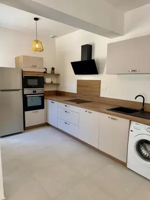 a kitchen with white cabinets and a washer at 4-bedroom house with a pool in LʼIsle-sur-la-Sorgue
