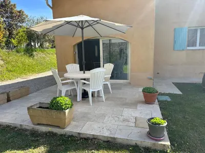 a patio with a table and chairs and an umbrella at Dépendance de charme avec piscine en luberon in Peypin-dʼAigues