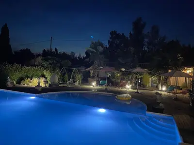 a blue swimming pool at night with lights at Le Mas de la Butte Blanche in Orgon