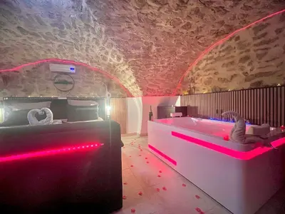 a room with a tub with pink lights in it at Secret LoveRoom - SpaBalnéo, Lit King Size, CLIM, Chic, calme et discret, 2 personnes in Saint-Chamas