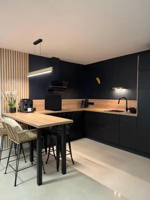 a kitchen with black cabinets and a wooden table at Ideal Cyclistes Km0 Ventoux RDC cour parking in Bédoin