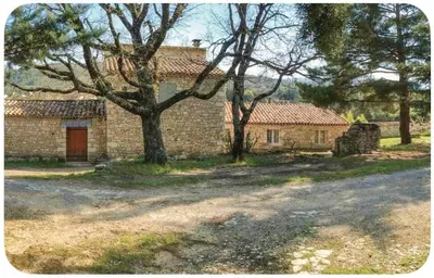 an old brick house with a tree in front of it at Maison provençale in Céreste