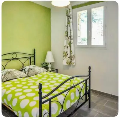 a green bedroom with a bed and a window at Maison provençale in Céreste