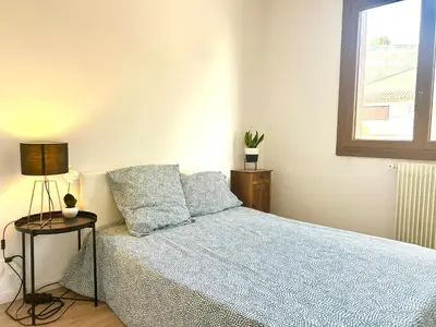 a bedroom with a bed with a blue comforter and a window at Superbe T4 proche Aix centre ville avec clim et parking in Aix-en-Provence
