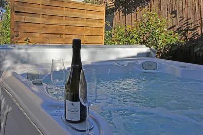 a bottle of wine and glasses in a hot tub at Havre de paix avec piscine & spa - proche Ventoux in Saint-Didier