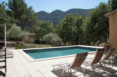 a swimming pool with two chairs and a swimming pool at Villa avec vue au pied du Luberon in Maubec