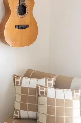 a guitar hanging on a wall above a couch with a pillow at Bali Style, Chic & Big Villa - Peaceful and Calm in Saint-Marc-Jaumegarde