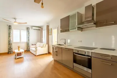 a kitchen with stainless steel appliances and a living room at L'Oustaou - Climatisé avec terrasse in Pélissanne