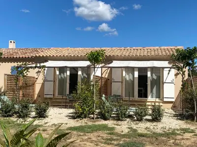a house with a white awning and palm trees at La Cigale et la Fourmi in Les Taillades