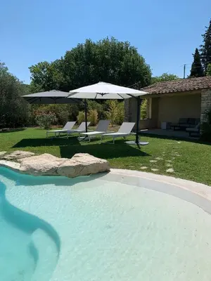 a swimming pool with an umbrella and two lounge chairs at La Bastide des Plâtrières in La Roque-sur-Pernes