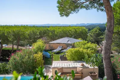 a garden with a couch and an umbrella and a vineyard at Mas Noves - Horizon Alpilles villa in Noves