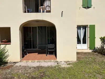 an entrance to a building with a patio with a table at Appartement Domaine du Golf de Pont Royal in Mallemort