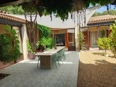 a patio with a wooden table and chairs in front of a house at Maison Maïtri in Lauris