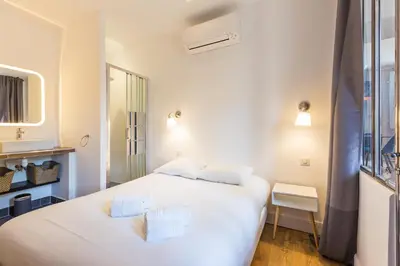 a bedroom with a large white bed and a window at Appartement centre ville, Air Conditionné, 2 suites, parking sur demande in Aix-en-Provence