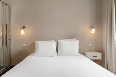 a bed with white sheets and pillows in a room at Appartement centre ville, Air Conditionné, 2 suites, parking sur demande in Aix-en-Provence