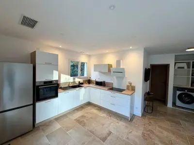 a large kitchen with white cabinets and a refrigerator at Le Nid in Châteaurenard