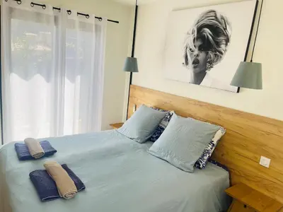 a bed with a blue and white comforter and pillows at Appart Ethan PROCHE DU CENTRE AVEC PARKING ET JARDIN in Aix-en-Provence