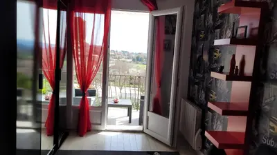 a door leading to a balcony with red curtains at Maison de charme in Pierrevert