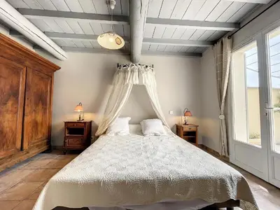 a bedroom with a white bed and a window at Maison LEA in Bédoin