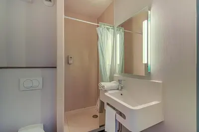 a white bathroom with a sink and a shower at B&B HOTEL Salon de Provence in Salon-de-Provence