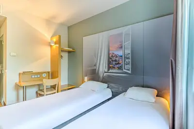 a room with two beds and a table and a desk at B&B HOTEL Salon de Provence in Salon-de-Provence