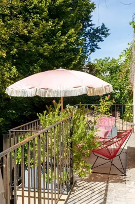 a patio with a red chair and an umbrella at La Magnanerie de l'Isle B&B in LʼIsle-sur-la-Sorgue