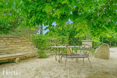 a table and chairs under a tree in a yard at Résidence Les Petitons in Oppède